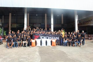 A commemorative photo of the natural rubber farmers behind the fertilizer they received